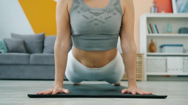 Laag schot van jonge vrouw die zonsalitatie yoga complex op mat thuis oefenen — Stockvideo