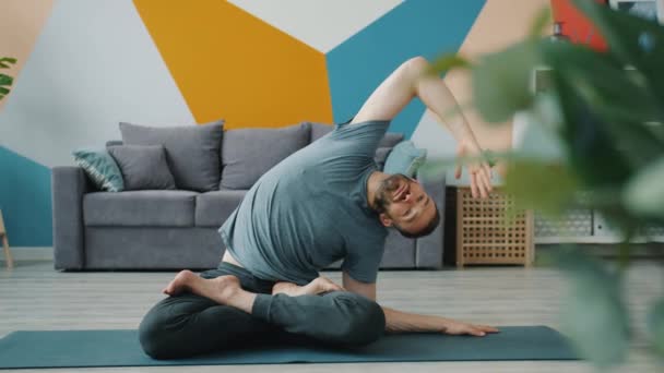 Slow motion of serious man bending sidewards in seated lotus position at home — Stock Footage Slow motion of serious man bending sidewards in seated lotus position at home Video Clip