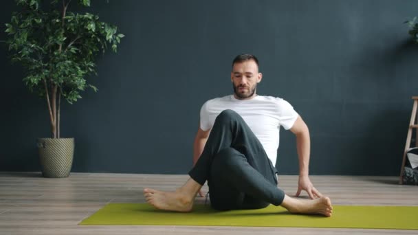 Maschio adulto che fa yoga da solo esercitandosi in posizione faccia di mucca nel centro benessere — Video Stock