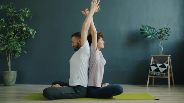 Schattig paar uit te werken in studio doen paar yoga samen zitten op mat binnen — Stockvideo