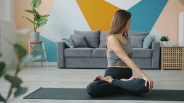 Çekici kadın yetişkin Lotus pozisyonunda çalışıyor yoga minderinde oturuyor.