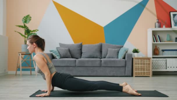 Gezonde jonge vrouw doet complex van yoga asanas thuis op comfortabele mat — Stockvideo