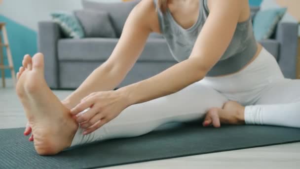 Zbliżenie ładna dziewczyna robi jogę w domu gięcia do nogi na macie w pozycji siedzącej — Wideo stockowe