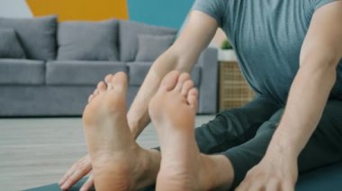 Evinde yoga yapan, viraj egzersizi yapan bir adamın yakın çekimi.