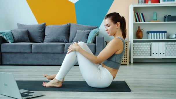Jonge dame met behulp van laptop om te leren yoga asanas kijken tutorial oefenen thuis — Stockvideo