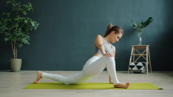 Hermosa joven haciendo ejercicio en interiores haciendo yoga sola en un estudio moderno — Vídeos de Stock