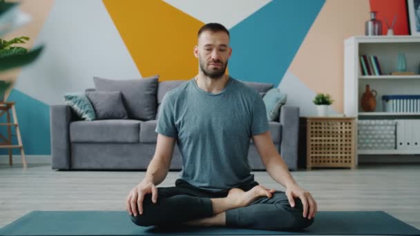 Heathy man stretching neck doing exercises at home on yoga mat caring for body — ストック動画