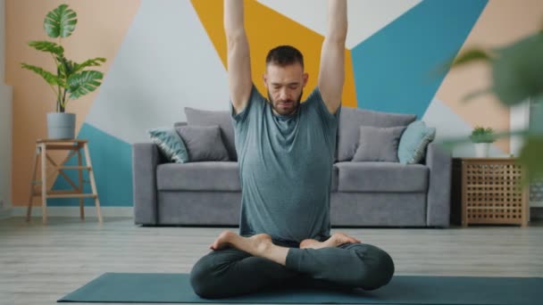 Guy doing arms balance in seated lotus position then relaxing with hands in namaste — ストック動画