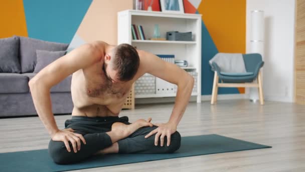 Парень тренирует мышцы живота, практикуя технику йогического дыхания дома — стоковое видео