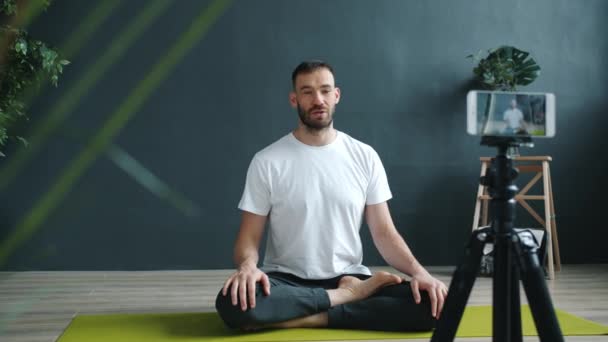 Professor de ioga masculino tutorial de gravação usando câmera de smartphone no estúdio moderno — Vídeo de Stock