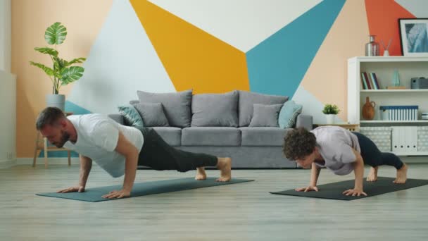 Male and female yoga students practice downward dog position at home — Stock video