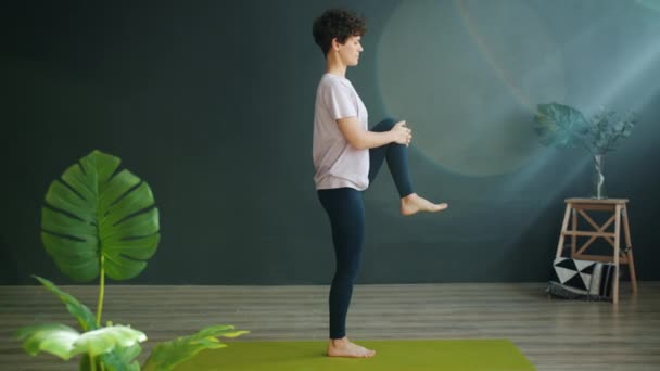 Atraktivní dospělá žena dělá jógu ve wellness studiu vyvážení na jedné noze relaxaci — Stock video
