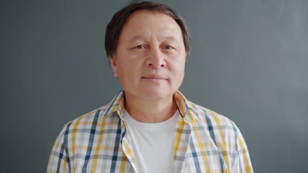 Retrato de adulto asiático en ropa casual mirando a la cámara sobre fondo gris — Vídeos de Stock