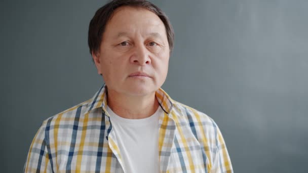 Portrait of sad Asian man standing alone in studio against dark background — 비디오