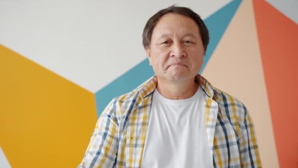 Heureux asiatique homme souriant montrant OK geste debout sur fond coloré — Video