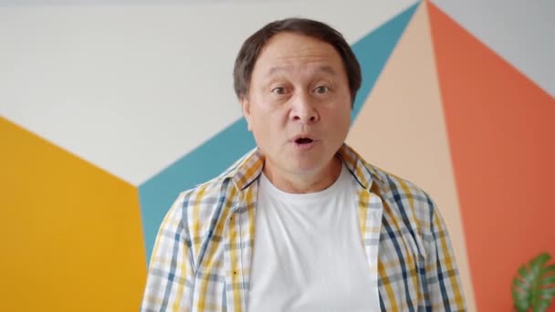 Opgewonden aziatische man het verhogen van vinger tonen goed idee gebaar op kleurrijke achtergrond — Stockvideo