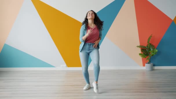 Красива азіатка танцює у світлій кімнаті з барвистими стінами. — стокове відео