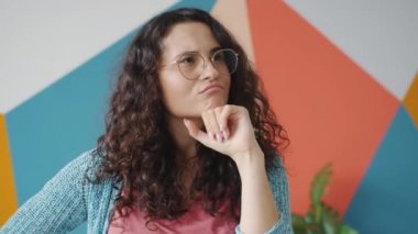 Yaratıcı kız düşünüyor ve parmaklarını kaldırıyor. Renkli arka planda harika bir fikri var.