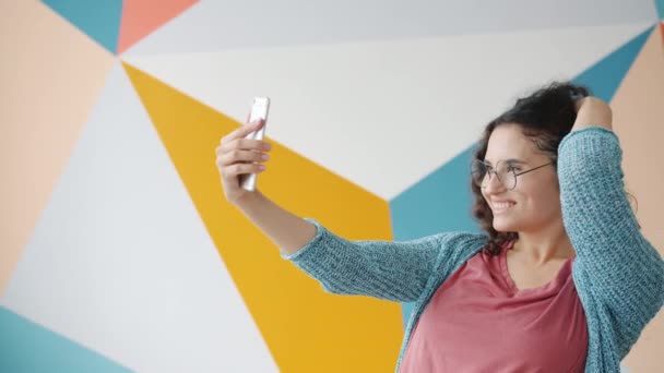 Retrato de chica asiática bonita tomando selfie con cámara de teléfono inteligente posando en el interior — Vídeos de Stock