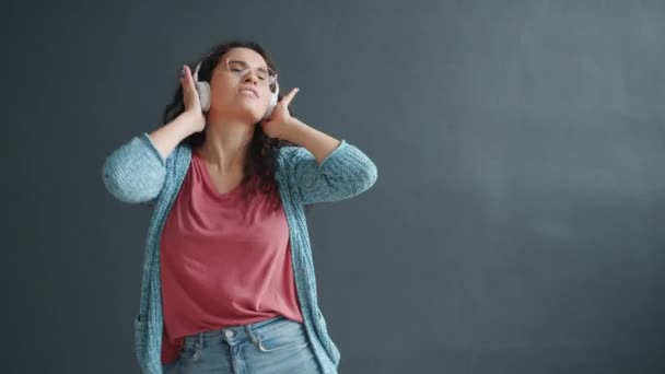 Gelukkig vrouw student dansen genieten van muziek in koptelefoon glimlachen — Stockvideo