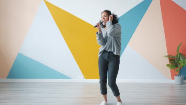 Lekfull afro-amerikansk kvinna njuter av musik dans sjunga i fjärrkontroll hemma — Stockvideo