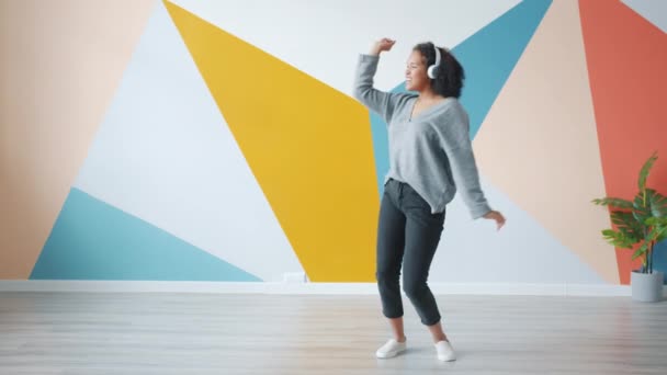 Cámara lenta de la mujer afroamericana bailando escuchando música a través de auriculares — Vídeo de stock