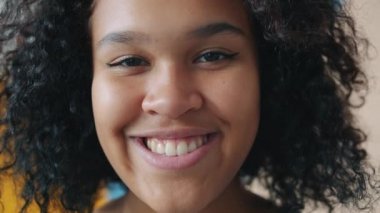İçerideki kameraya gülümseyen Afro-Amerikan kadının yüz resmi.