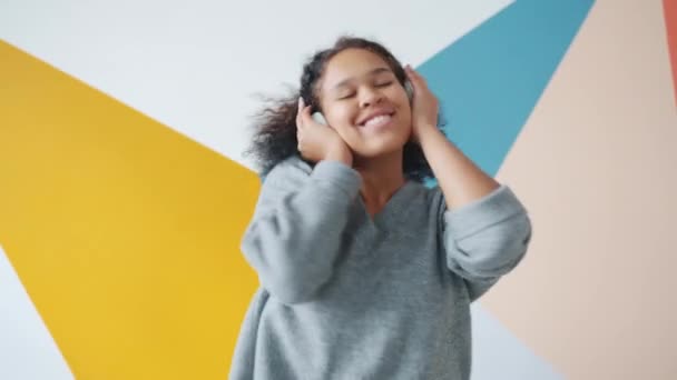 Retrato de un alegre estudiante afroamericano bailando con auriculares en el interior — Vídeos de Stock