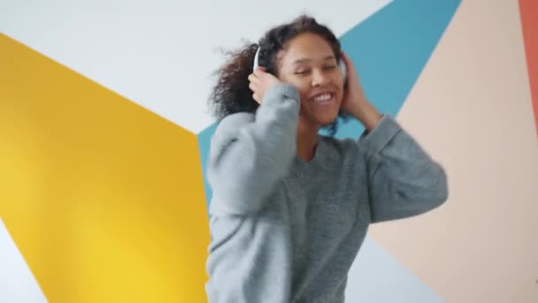 Portret afro-amerykańskiej dziewczyny tańczącej słuchając muzyki na kolorowym tle — Wideo stockowe