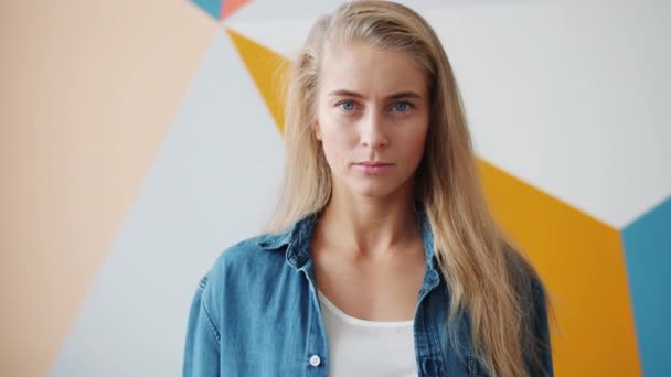 Zeitlupe einer attraktiven Blondine mit blauen Augen, die mit ernstem Gesicht in die Kamera blickt — Stockvideo