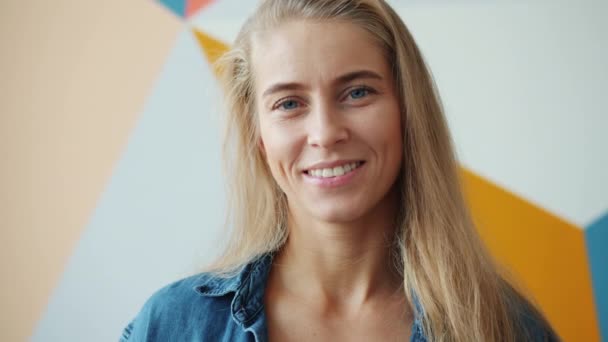Portret uroczej blondynki z niebieskimi oczami uśmiechniętymi na kolorowym tle uczucie szczęścia — Wideo stockowe