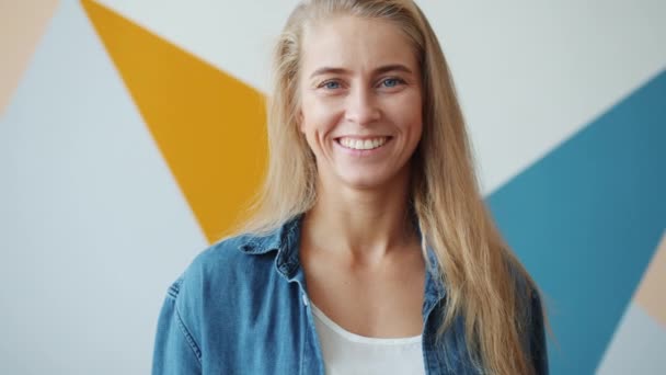 Portret van aantrekkelijke vrolijke jonge dame blond glimlachen op kleurrijke achtergrond — Stockvideo