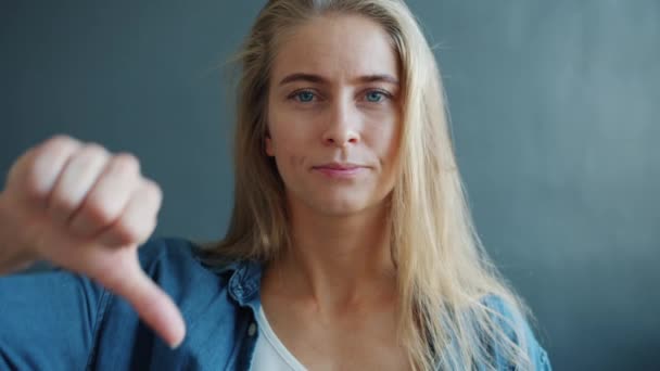 Porträt einer enttäuschten Frau, die unglücklich aussehende Daumen-nach-unten-Geste zeigt — Stockvideo