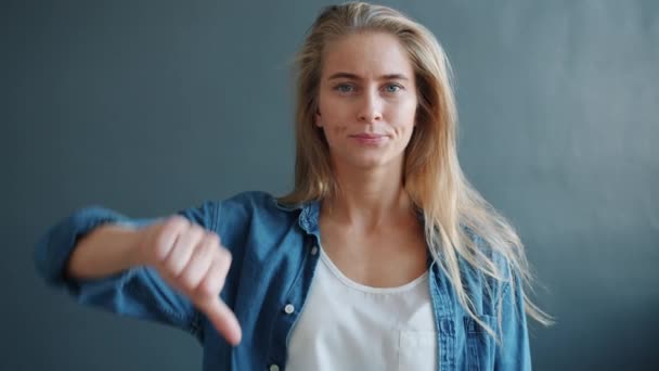 Retrato de una mujer guapa mostrando un gesto de aversión levantando el brazo con los pulgares hacia abajo — Vídeo de stock