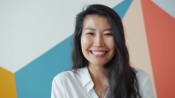 Vonzó ázsiai nő felnőtt mosolyog otthon nevet színes háttér — Stock videók