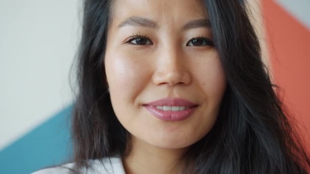 Close-up portret van charmante Aziatische dame glimlachen op kleurrijke achtergrond alleen — Stockvideo