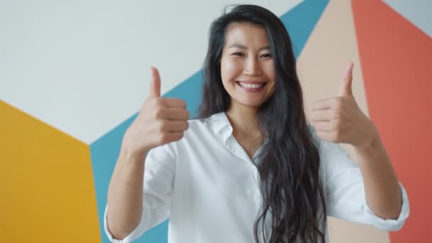 Retrato de feliz mujer de negocios asiática mostrando el gesto de los pulgares hacia arriba con ambas manos — Vídeos de Stock