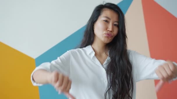 Cámara lenta de la mujer asiática mostrando el gesto de los pulgares hacia abajo con ambas manos — Vídeos de Stock