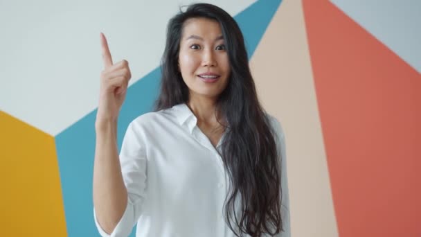 Retrato de mujer asiática creativa levantando el dedo sintiéndose feliz teniendo una gran idea — Vídeos de Stock