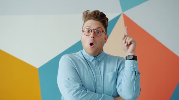 Creatieve kerel het verhogen van de vinger met een goed idee vinden van oplossing op kleurrijke achtergrond — Stockvideo