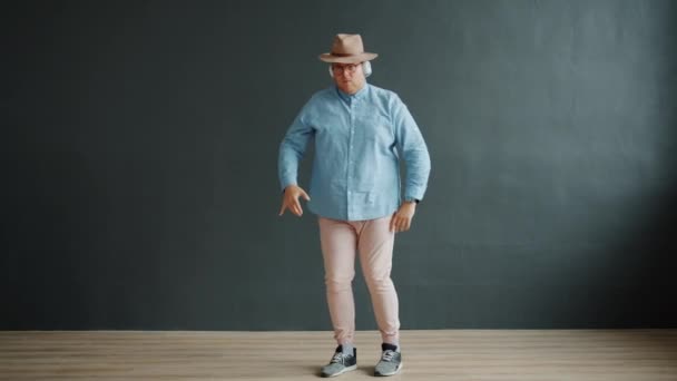 Мужчина танцующий робот в шляпе и очках на темно-сером фоне — стоковое видео
