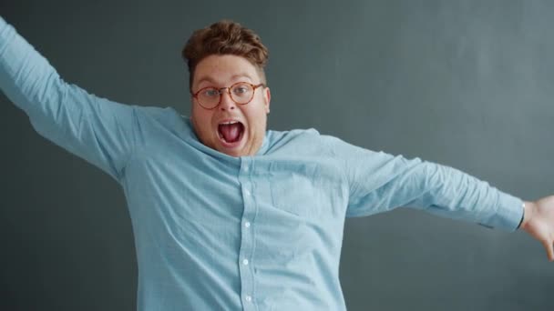 Playful actor having fun on gray background showing funny faces grimaces moving arms — Stock Video