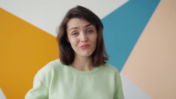 Zeitlupe unglücklicher Frau mit Daumen-nach-unten-Geste auf buntem Hintergrund — Stockvideo