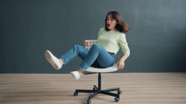 Портрет беззаботной дамы, вращающейся на стуле в студии, наслаждающейся забавной активностью — стоковое видео
