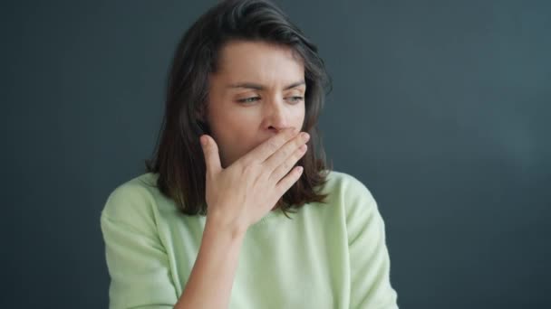 睡意朦胧的女士在深灰色背景下独自看着相机的画像 — 图库视频影像