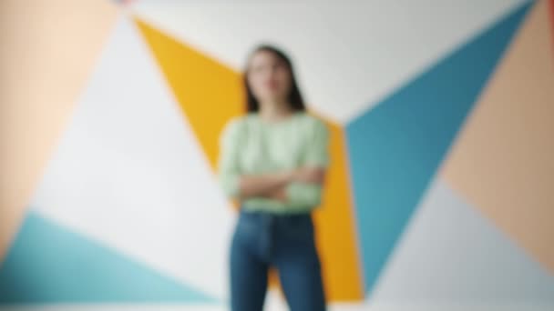 Zoom-in πορτρέτο της γοητευτικής κομψής κυρίας που στέκεται σε εσωτερικούς χώρους σε πολύχρωμο φόντο — Αρχείο Βίντεο
