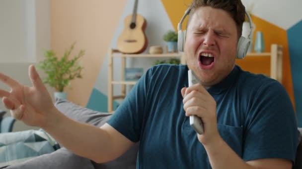 Emocional hombre cantando en control remoto usando auriculares disfrutando de la canción — Vídeos de Stock