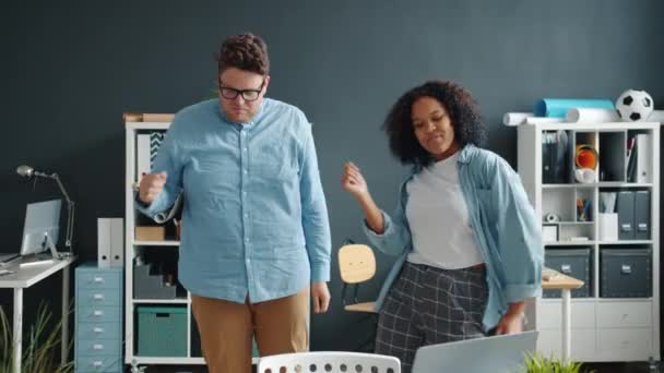 Vreugdevolle collega 's man en vrouw dansen in kantoor het hebben van plezier binnen samen — Stockvideo