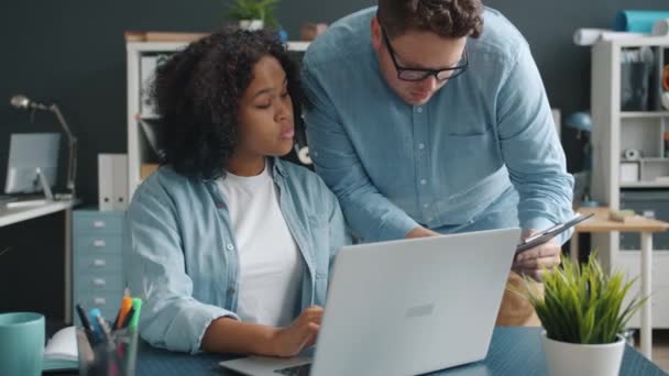 Trabalhadores de escritório masculinos e femininos conversando usando laptop dentro de casa em sala de co-trabalho — Vídeo de Stock