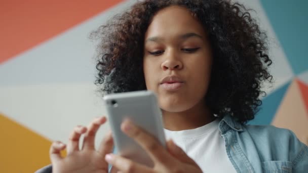 Attractive girl holding smartphone touching screen at home on colorful background — 비디오